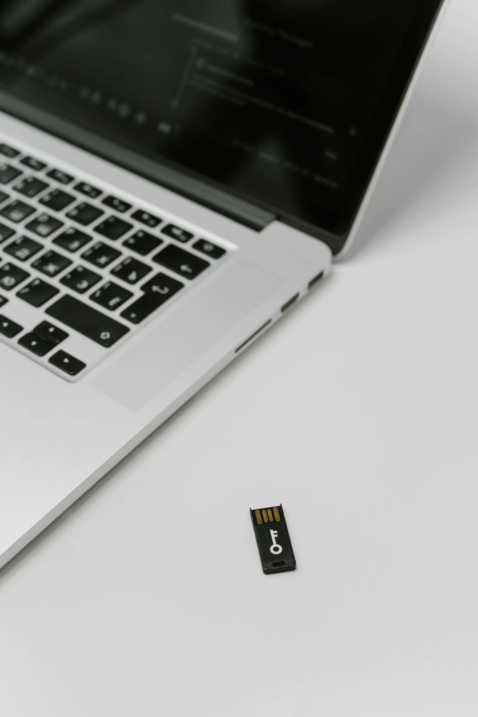 A laptop on a desk next to a hardware security key