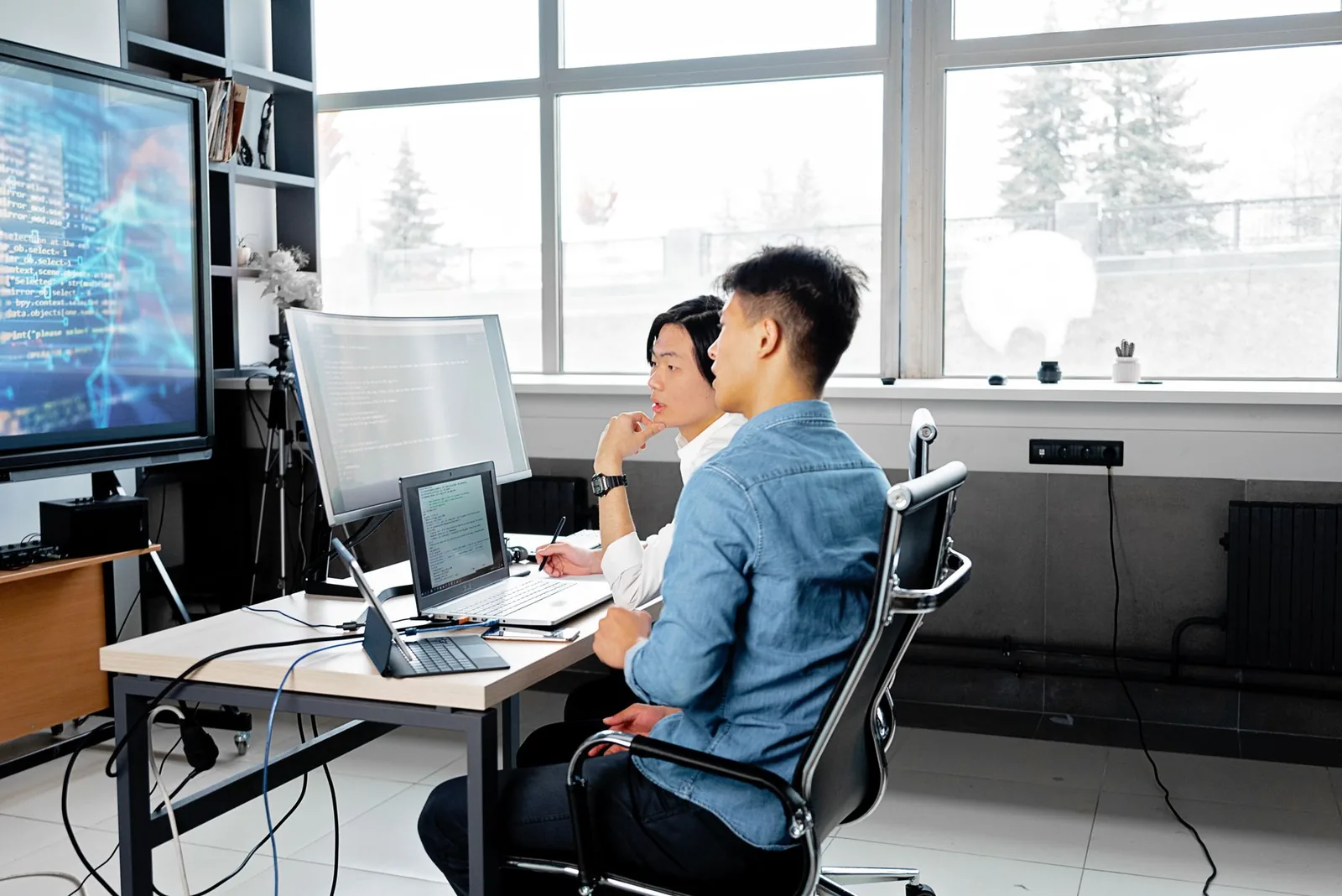 Engineers working at multi-monitor desks in a bright office
