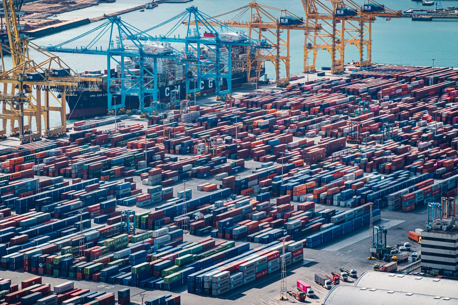 Gantry cranes and stacked shipping containers at a busy port terminal
