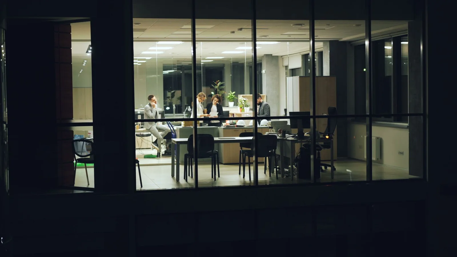 A lit meeting room seen through the glass frontage of an office at night